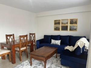 Zoe Homes Oak Villa Apartment 1 and 2 Bedroom 201 في Kericho: غرفة معيشة مع أريكة زرقاء وطاولة