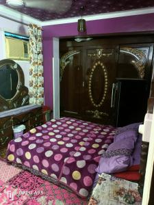 1 dormitorio con cama morada y cabecero de madera en sun Ahmed hotel, en ‘Ezbet Abu Ḥabashi