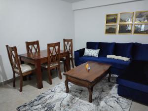 Zoe Homes Oak Villa Apartment 1 and 2 Bedroom 201 في Kericho: غرفة معيشة مع أريكة زرقاء وطاولة