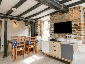 a dining room with a table and a tv on a stone wall at The Retreat in Bideford