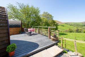 eine Holzterrasse mit einem Tisch und Stühlen darauf in der Unterkunft Ty Grug Pods in Bryngwyn