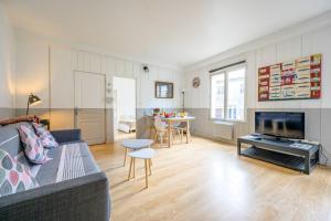 a living room with a couch and a tv and a table at Au cœur de St Martin : Les Grenettes in Saint-Martin-de-Ré