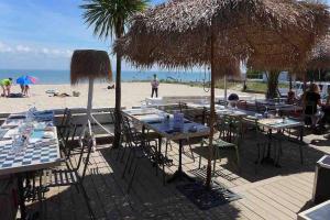 a group of tables with umbrellas on the beach at Au cœur de St Martin : Les Grenettes in Saint-Martin-de-Ré