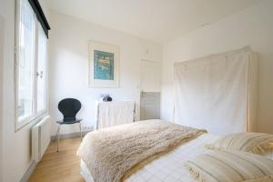 ein weißes Schlafzimmer mit einem Bett und einem Stuhl in der Unterkunft Au cœur de St Martin : Les Grenettes in Saint-Martin-de-Ré