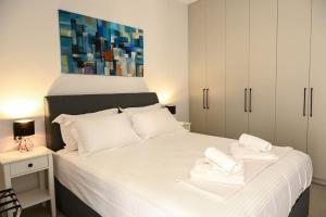 Larisa Hospitality II - St Nicholas apartment - with Free Parking في لاريسا: غرفة نوم بسرير ابيض عليها منشفتين