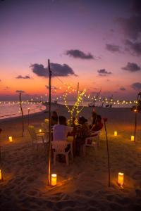 un grupo de personas sentadas en una mesa en la playa en Nemo Inn, en Omadhoo