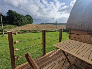 a wooden bench sitting on a porch looking at a field at Chalet du bonheur de campagne 