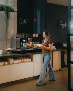 a woman standing at a counter in a coffee shop at Le Dauphin Montréal Centre-Ville in Montreal