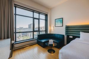 Habitación de hotel con cama, silla y ventana grande. en Le Dauphin Montréal Centre-Ville, en Montreal