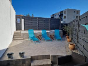 un patio con sillas azules, una mesa y una valla en Villa Carmen, en Pula