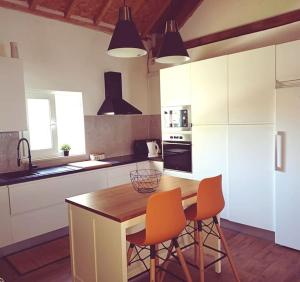 kuchnia z drewnianym stołem i 2 pomarańczowymi krzesłami w obiekcie Casa da Ribeira w mieście Alcanede
