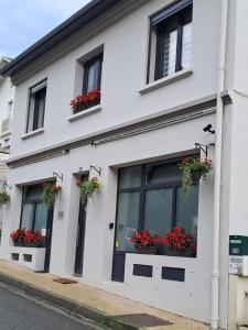 un edificio blanco con flores en las ventanas en La Maison de Jeanne, en Capvern