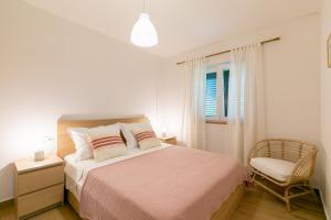 une chambre blanche avec un lit et une chaise dans l'établissement Apartment near the beach- Zen 2, à Brna