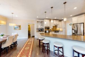 a kitchen with white cabinets and a bar with stools at Cape Castle in Mashpee