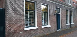 a brick building with three windows on a street at Tante roosje in Enkhuizen