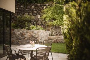 a white table with chairs and a stone wall at Milla Apartments in Bressanone
