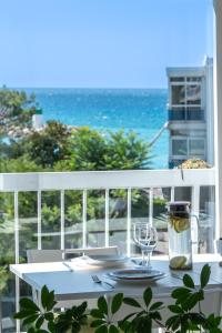 een witte tafel met een glas wijn op een balkon bij Résidence méditerranée - Beachfront - Sun and Seaview - Pool - Private Parking in Cagnes-sur-Mer