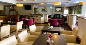 ein Restaurant mit Tischen, rosa Stühlen, Tischen und Stühlen in der Unterkunft Hannon's Hotel in Roscommon