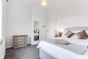 a white bedroom with two beds and a dresser at Victorian Terrace, East Ardsley in Robin Hood