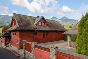a large wooden house with mountains in the background at Chalupa Beliankovo Ždiar in Ždiar