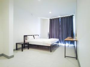 a bedroom with a bed and a table and a window at GO INN HuaHin โกอินน์ หัวหิน in Hua Hin