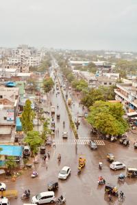 una calle concurrida en una ciudad con coches y gente en Hotel Oberon en Solapur