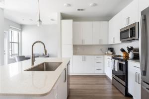 a white kitchen with white cabinets and a sink at Eden Ruby Lake 1 bedroom in Orlando