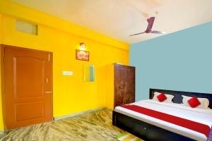 - une chambre avec un lit aux murs jaunes et une porte dans l'établissement OYO Flagship Hotel Elite Inn, à Bhubaneswar