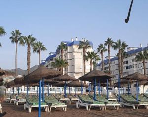 ein paar Stühle und Sonnenschirme am Strand in der Unterkunft Frente al mar in Benalmádena