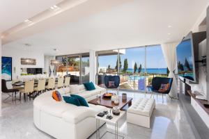 una sala de estar con muebles blancos y vistas al océano. en Annabel Beach Palace, en Lachi