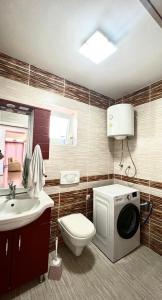 y baño con aseo y lavadora. en Prishtina rental house en Pristina