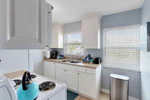 a white kitchen with white cabinets and a sink at Beachside 16 in Indian Harbour Beach