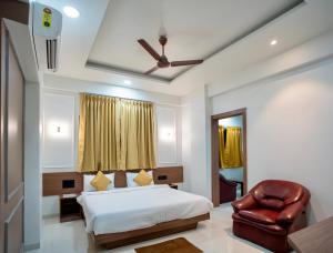 a bedroom with a bed and a leather chair at Hotel Oberon in Solapur