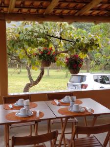a table with two chairs and a window with a tree at Pousada Águas da Canastra in Vargem Bonita