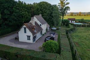 een klein wit huis met een auto ervoor geparkeerd bij La Maison Cornière in Biéville-en-Auge