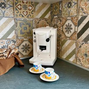 a coffee espresso machine with two cups on the floor at Scapriccio Relax in Serrara Fontana