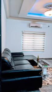 - un salon avec un canapé en cuir noir et une table dans l'établissement Appart de deux chambres salon scindé en cour unique à louer, à Lomé