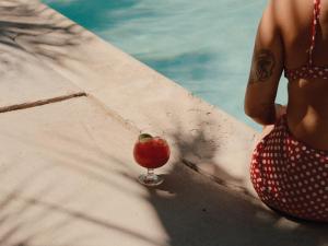 Life House, Palm Springs في بالم سبرينغز: امرأة جالسة بجوار الشراب على حافة