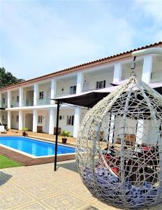 une grande boule de métal assise à côté d'une piscine dans l'établissement Hotel Kenito, à São Tomé