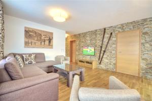 a living room with a couch and a stone wall at Alpin & Seeresort Top 10 - by Alpen Apartments in Zell am See
