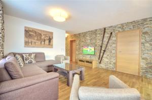 salon z kanapą i kamienną ścianą w obiekcie Alpin & Seeresort Top 10 - by Alpen Apartments w mieście Zell am See
