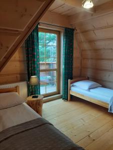 ムジャシフレにあるGóralski Domek z kominkiem - Highlander Wooden Houseのベッドルーム1室(ベッド2台、窓付)