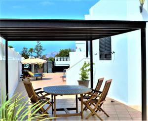 a patio with a table and chairs on a balcony at Grand Villa Famara Los Mojones by Dolores in Puerto del Carmen