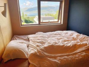 an unmade bed in a room with a window at Northstay - House of Northern Lights in Tromsø