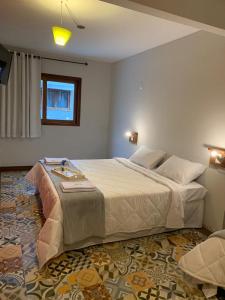 um quarto com uma cama grande e uma janela em Pousada Lazúli em Macaé
