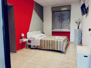 1 dormitorio con cama y pared roja en B&B La Stazione en Sibari
