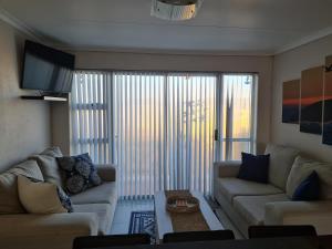 un salon avec deux canapés et une grande fenêtre dans l'établissement Hermanus Beach Club UNIT 74, à Hermanus