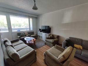 uma sala de estar com sofás e uma televisão em Cozy budget room w/ balcony in shared apartment em Vantaa