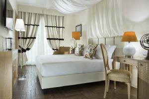 a bedroom with a white bed and a desk and a chair at Erbavoglio Hotel in Rimini