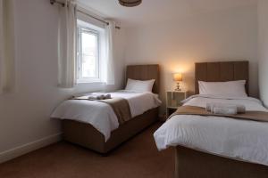 1 dormitorio con 2 camas y ventana en comfortable 4 bedroom house in Aylesbury ideal for contractors, proffesionals or bigger family, en Aylesbury